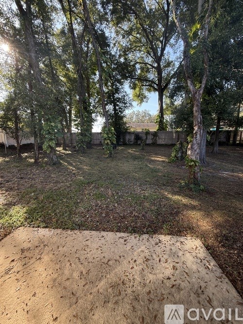 A backyard with a wooden deck and trees.
