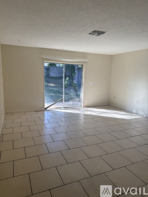 A room with a tiled floor and a sliding glass door leading outside.