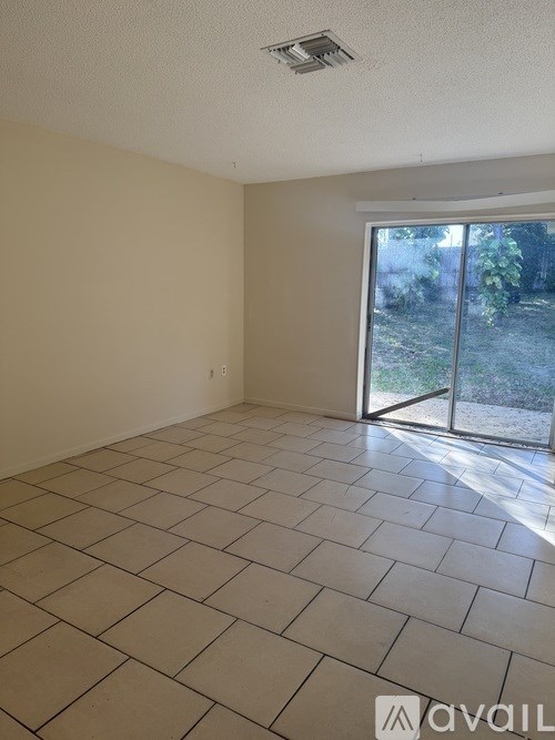 A room with a tiled floor and a sliding glass door leading to a garden.