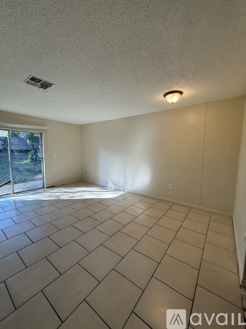 A room with a tiled floor and a sliding glass door leading outside.
