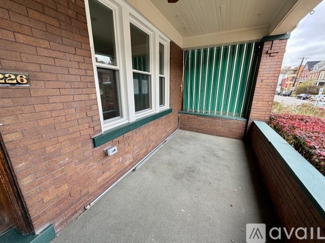 A balcony with a brick wall and a window with green blinds.