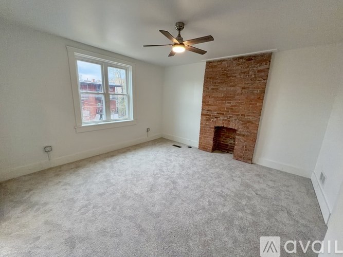 A room with a ceiling fan and a window with a view of a snowy street outside.