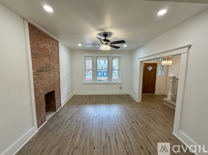 A room with a brick fireplace and wooden flooring.