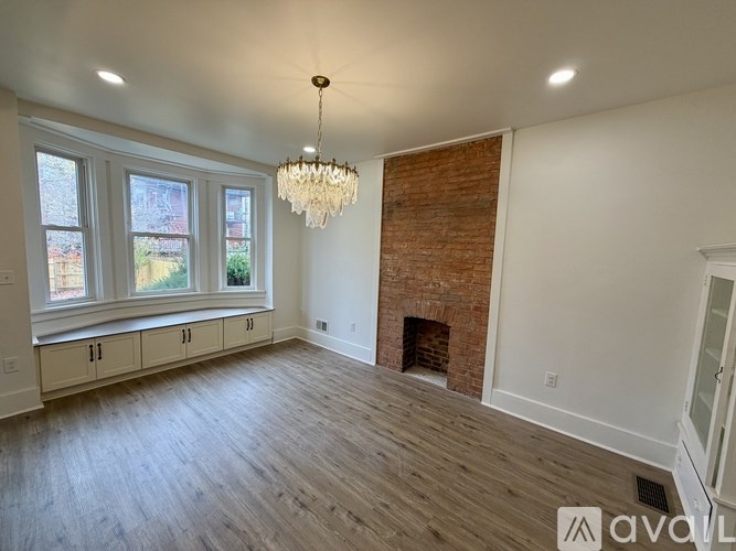 A large, empty room with a fireplace and a chandelier.
