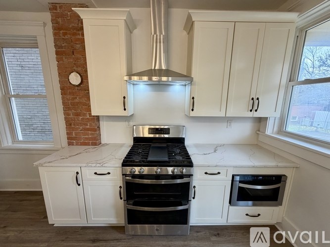 A kitchen with white cabinets and a brick wall.
