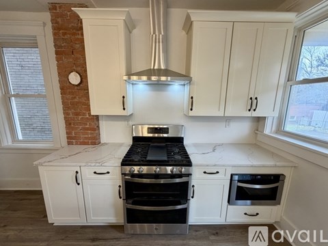A kitchen with white cabinets and a brick wall.