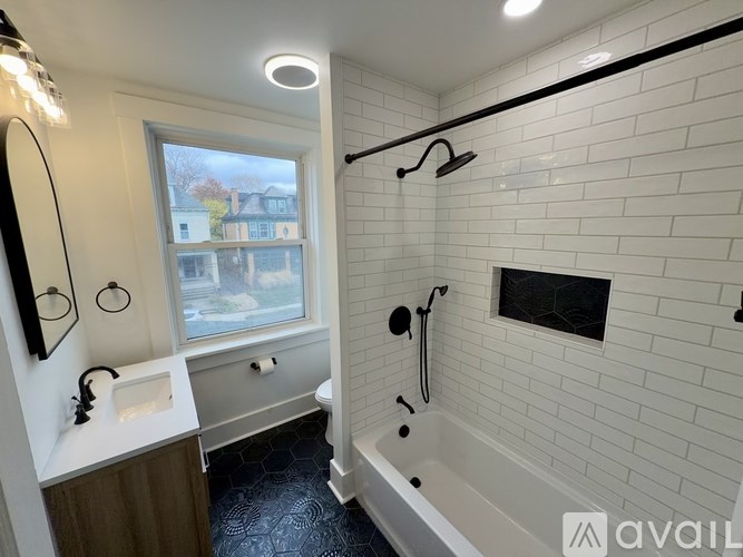 A bathroom with a white tub and black tiles.