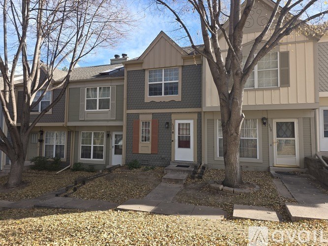 A row of houses with trees in front.