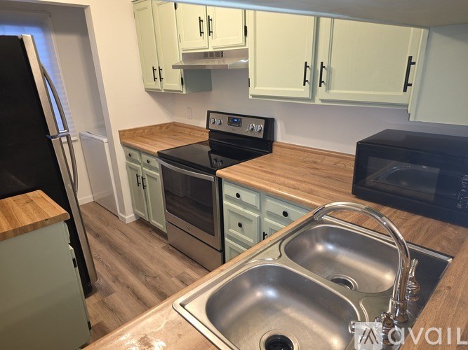 A kitchen with a black fridge, black oven, and a black microwave.