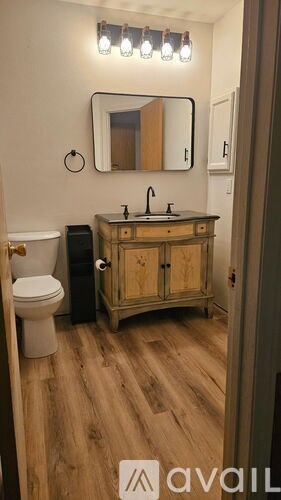 A bathroom with a wooden vanity and a round mirror on the wall.