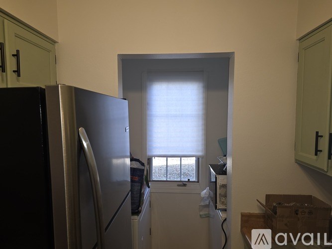 A kitchen with a black fridge and a window letting in light.