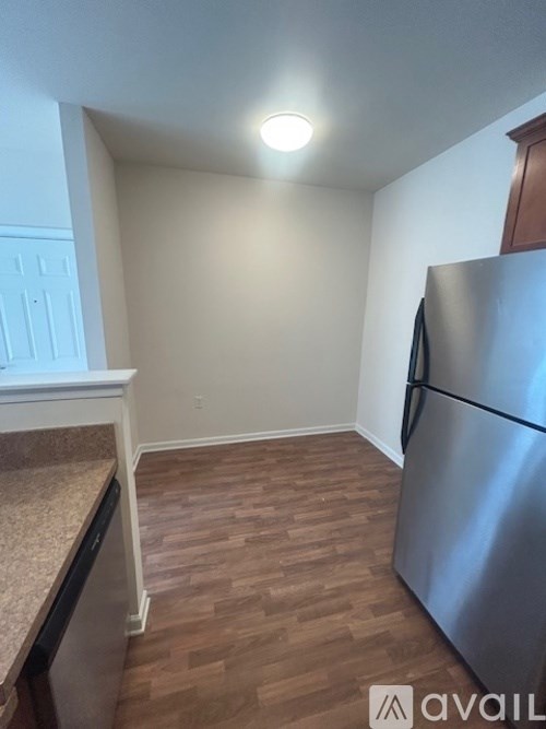 A kitchen with a stainless steel refrigerator and wooden flooring.