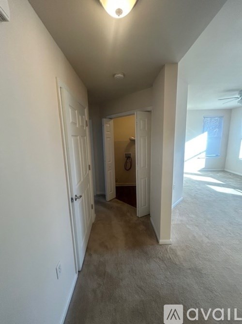 A hallway with a carpeted floor and white walls.