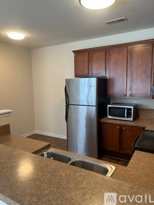 A kitchen with a refrigerator, microwave, and a sink.