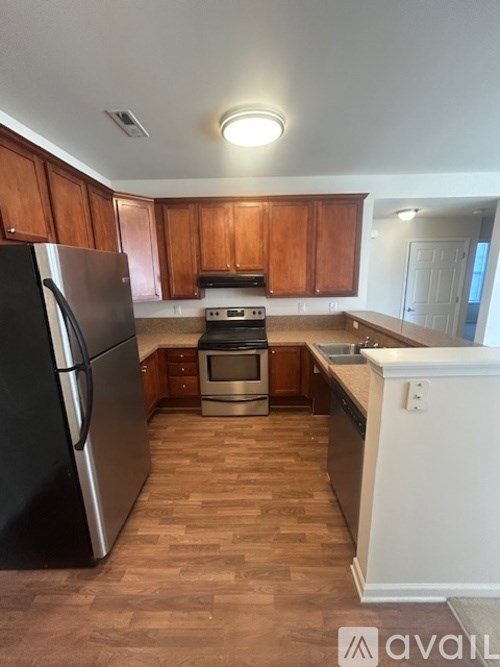 A kitchen with wooden cabinets and a black refrigerator.