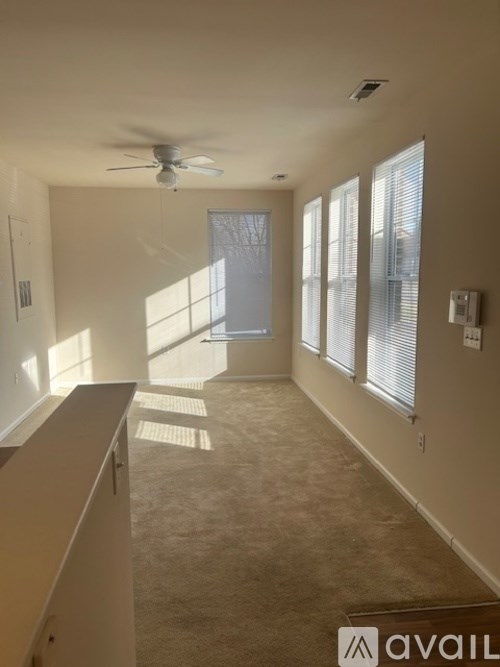 A spacious room with a ceiling fan and large windows.