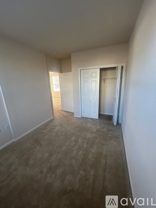 A room with a white door and a brown floor.
