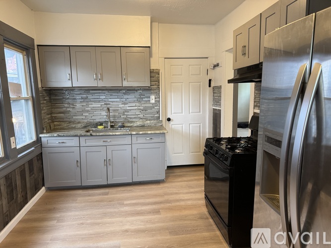 A kitchen with a black stove top oven and a refrigerator.