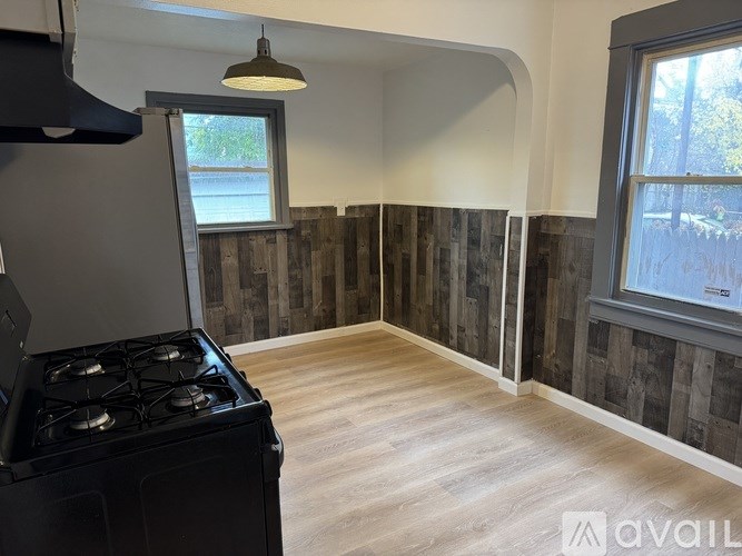 A black stove is in a room with wooden floors and a window.