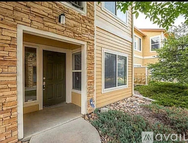 A house with a brown brick wall and a glass door is for sale.