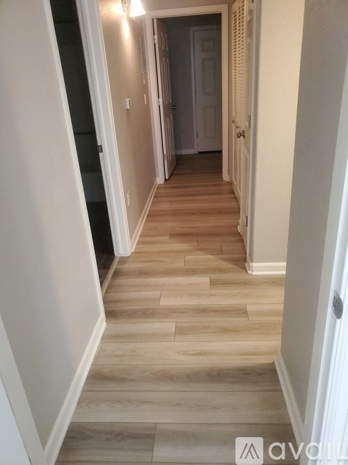 A hallway with wooden floors and white walls.