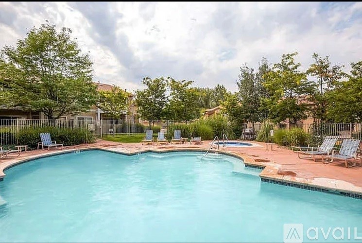 A large outdoor swimming pool surrounded by lounge chairs and trees.
