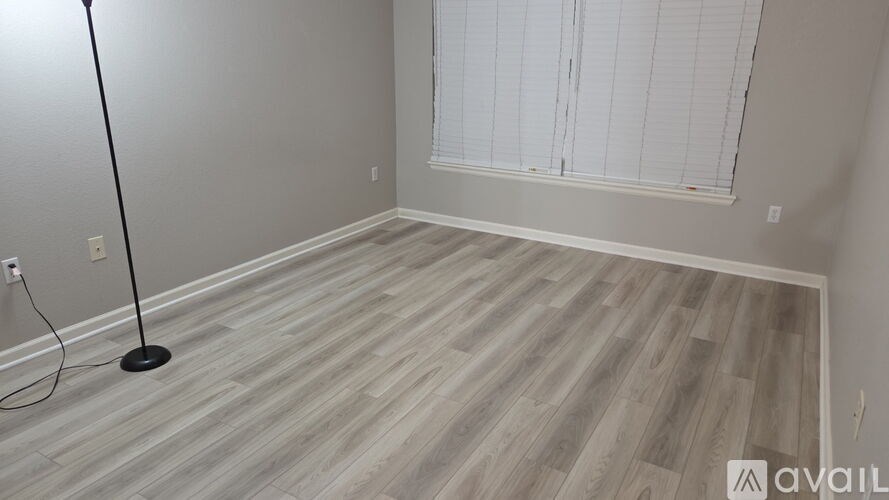 A room with wooden flooring and a window with blinds.