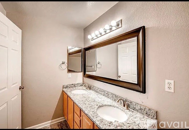 A bathroom with a granite countertop and a large mirror above it.