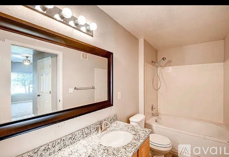 A bathroom with a marble countertop and a large mirror above it.