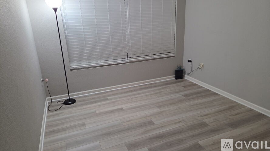 A room with a wooden floor and a window with blinds.