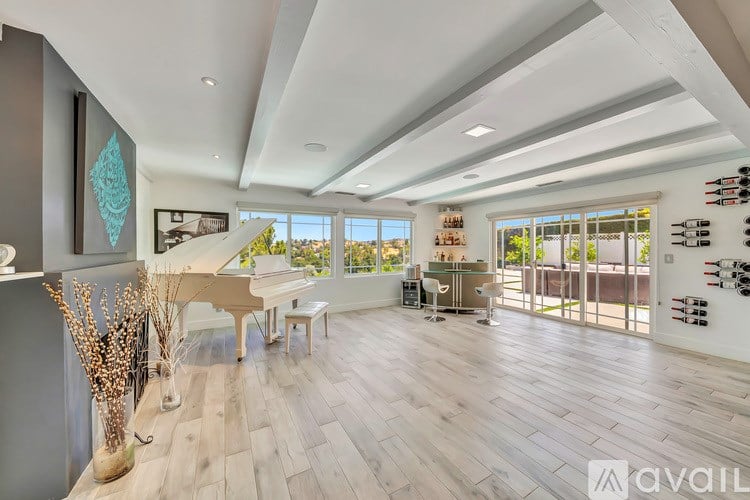A spacious living room with a grand piano and a view of the outdoors.