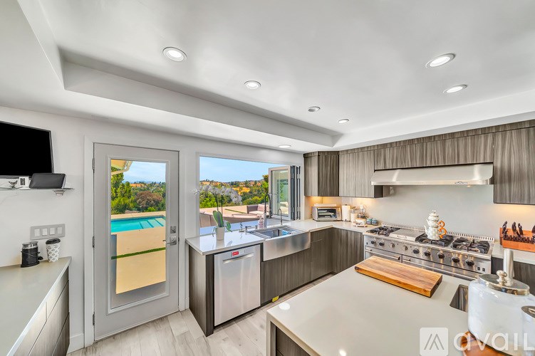 A modern kitchen with a large island and a view of the pool outside.