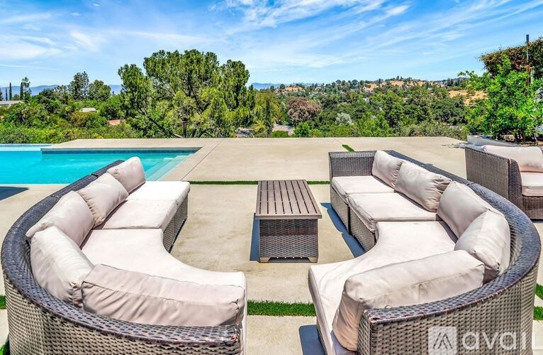 A patio with a pool and furniture is set in a natural landscape.