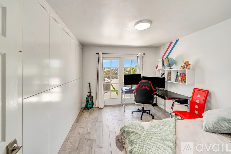A room with a desk, chair, and a guitar.