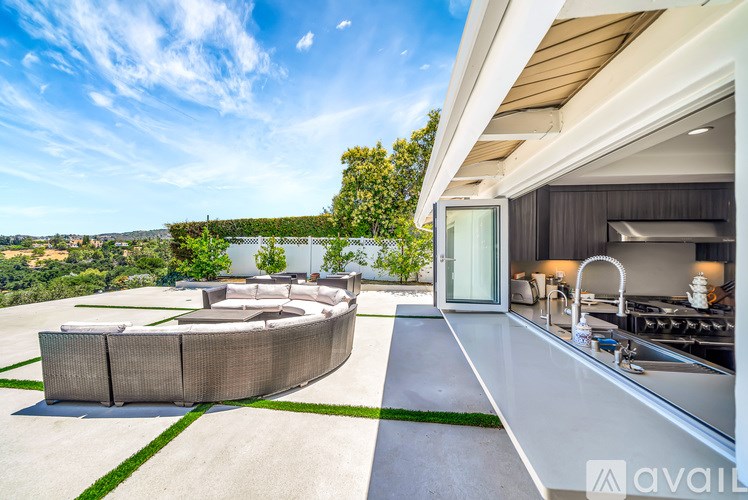 A modern outdoor kitchen with a large island and a view of the city in the distance.