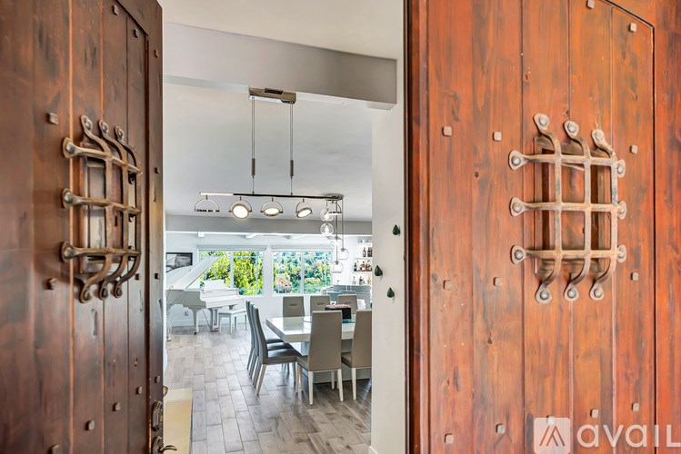 A wooden door with a metal handle is open to a dining room.