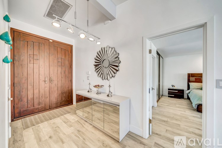 A bedroom with a bed, nightstand, and a large mirror on the wall.