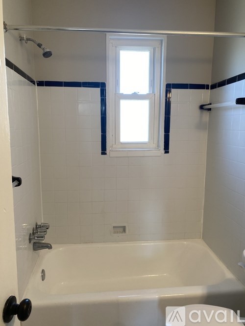 A white bathroom with a tub and a window.