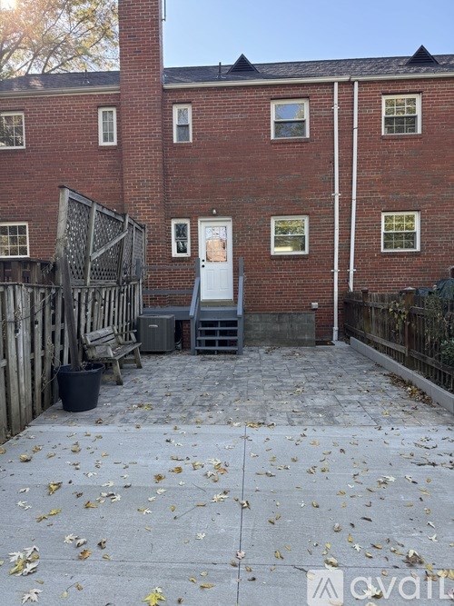 A brick building with a gate and a trash can in front.