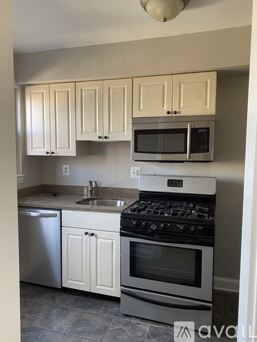 A kitchen with a stove, sink, and cabinets.