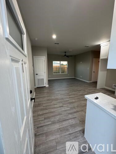 A spacious room with wooden flooring and white walls.