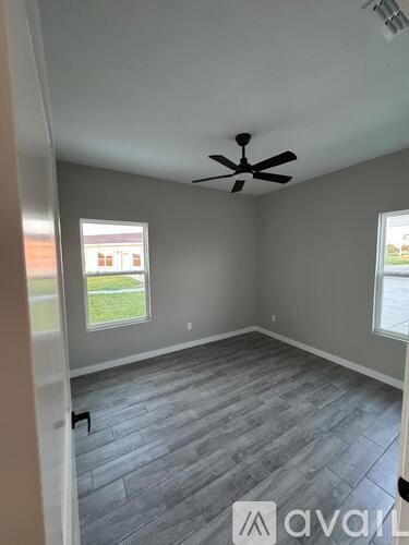 A room with a ceiling fan and two windows.
