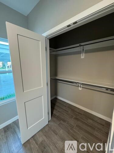 A white door is open to a room with a grey wall and a grey carpet.