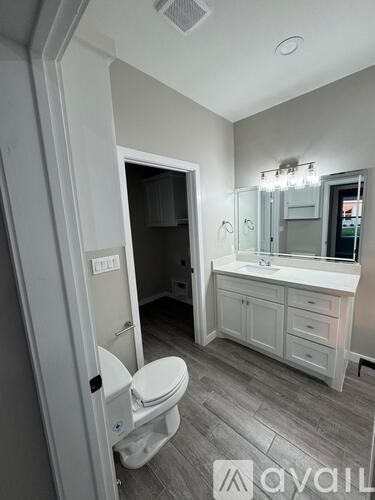 A bathroom with a toilet, sink, and mirror.