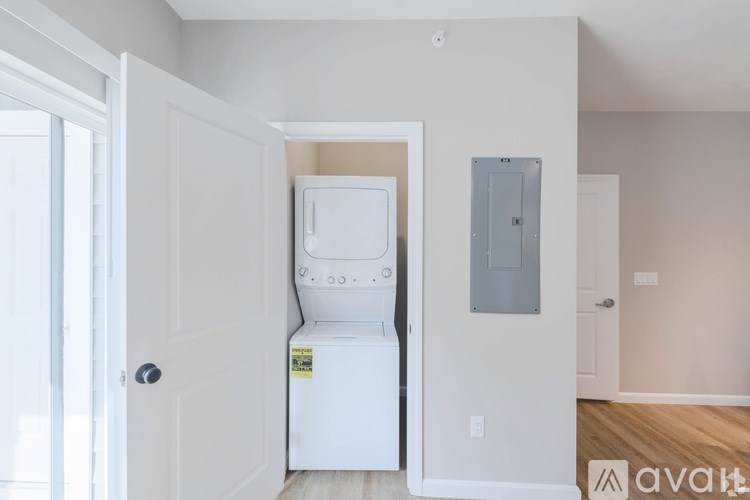 A white fridge in a room with a door and a wall socket.