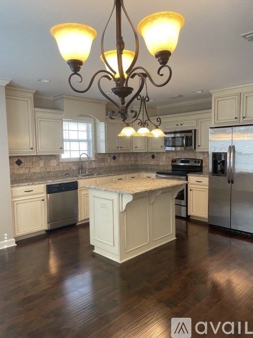 A kitchen with a center island and a chandelier hanging from the ceiling.