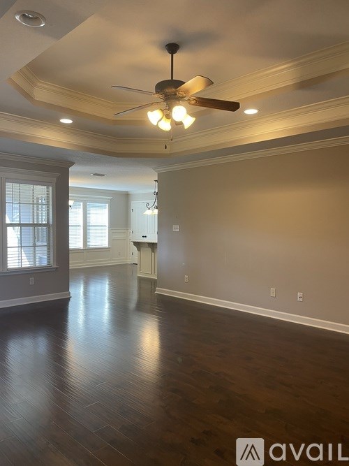 A room with a ceiling fan and wooden flooring.