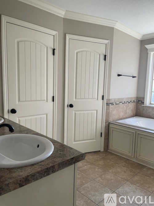 A bathroom with a sink, two doors, and a tub.