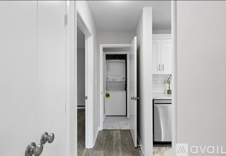A white door is open to a kitchen with a fridge and dishwasher.