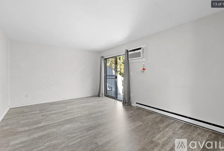 A room with a wooden floor and a sliding glass door leading outside.